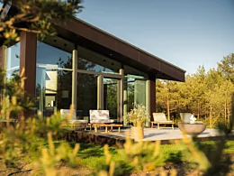 Modern outdoor living space with the contemporary Mix 850 fire pit creating warmth and atmosphere on a patio beside a glass-walled home